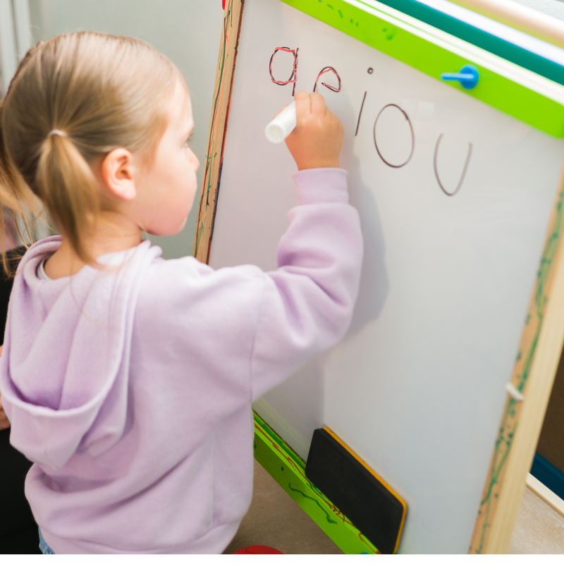 Shoulder stability + control activities, child writing on vertical whiteboard