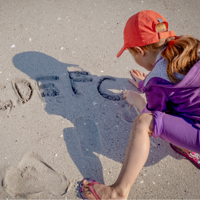 Drawing + Writing in Everyday Activities, child writing letters in sand